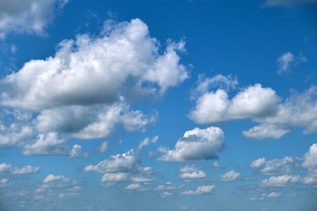 Bright landscape of white puffy cumulus clouds on blue clear sky.