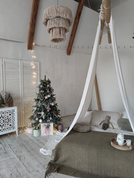 Bright large bedroom New Year's interior New Year's tree by the bed is decorated with balls Chris