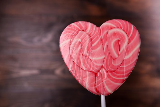 Photo bright lollipop in shape of heart on wooden background