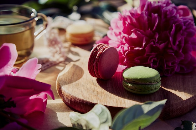 Bright macarons dessert and herbal tea for brunch in the terrace blooming pink peony flowers