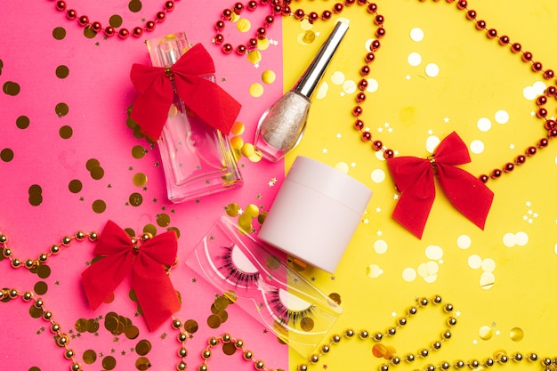 Bright makeup and perfume layout on half pink and half yellow background