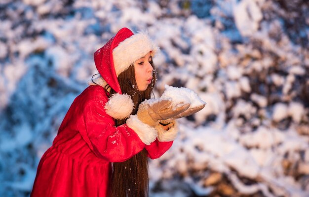 Photo bright memories little girl enjoy season small girl in santa costume play with snow snowy winter nature happy new year child in warm mittens spend winter holiday with joy santa claus helper