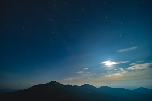 The bright moon in a starry sky above mountains