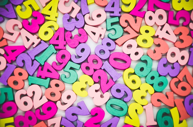 Bright multicolored background of wooden numbers from zero to nine. Top view, abstract colorful texture with numbers. Concept: back to school, math.