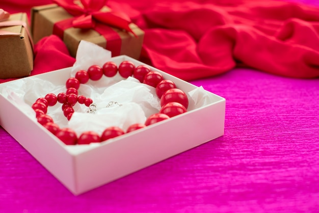 Bright necklace is Packed in a white box on a pink background.