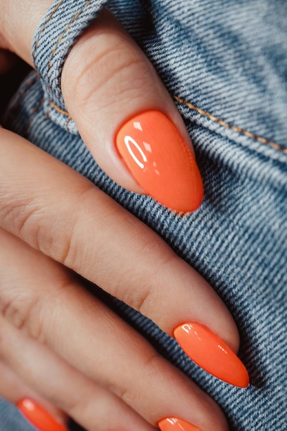 Photo bright neon manicure on female hands on the background of jeans nail design