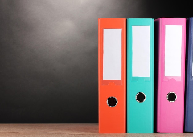 Bright office folders on wooden table on grey background