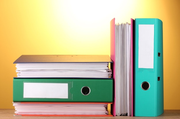 Bright office folders on wooden table on yellow background