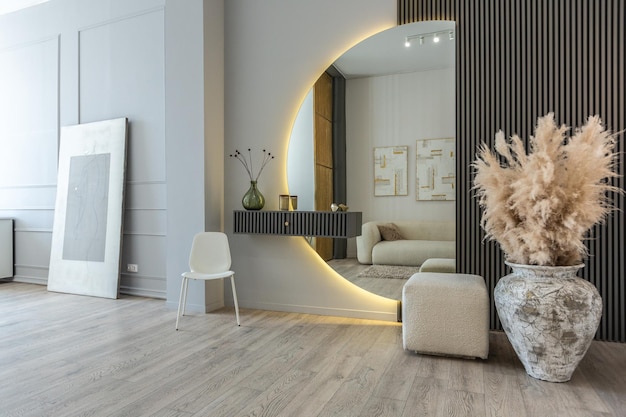 Bright openplan apartment in a modern design light walls and wooden floor stylish entrance hall with a beautiful vase and a round mirror and a sofa for guests