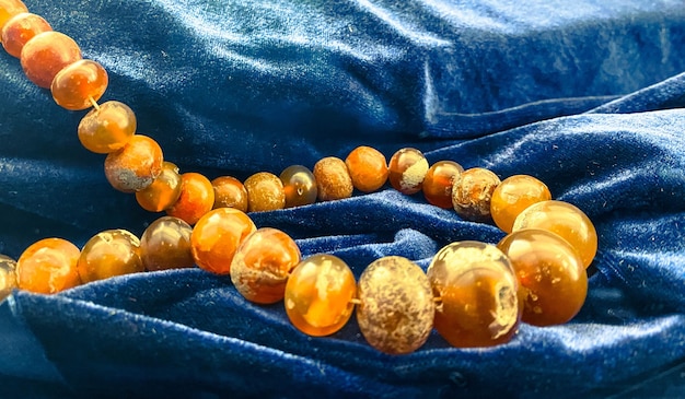 Bright orange amber beads on a blue velvet backing museum exhibit on a pedestal jewelry