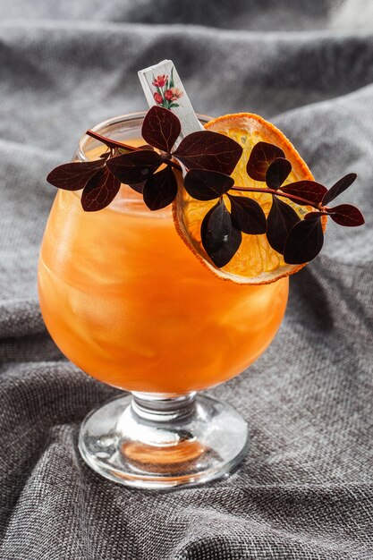 Bright orange Old Fashioned Cocktail with whiskey on a gray