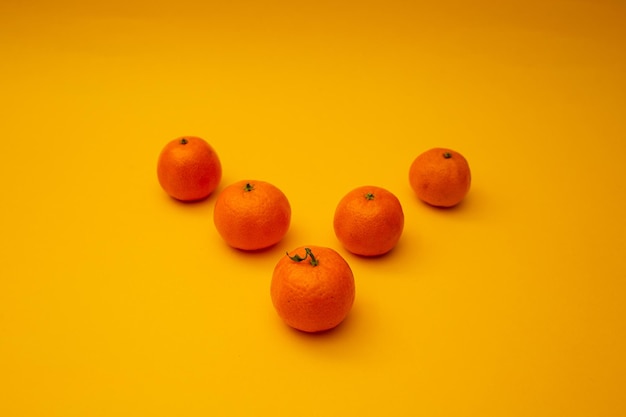 Bright orange tangerines lie on a yellow background