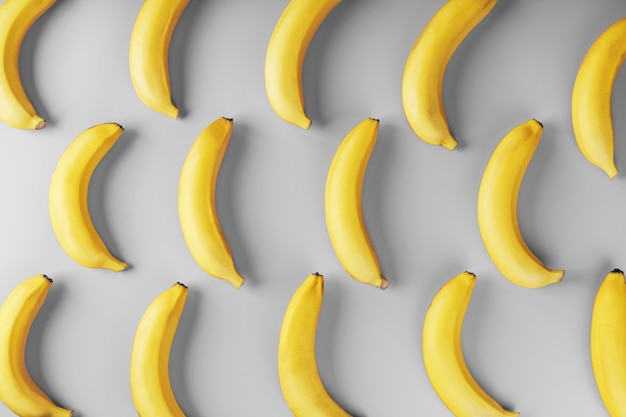 Bright pattern of yellow bananas on a gray background. View from above. Flat lay. Fruit patterns