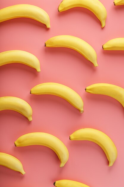 Bright pattern of yellow bananas on a pink background. View from above. Flat lay. Fruit patterns