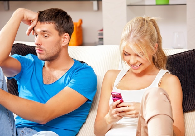 bright picture of couple at home with cellphone (focus on woman)