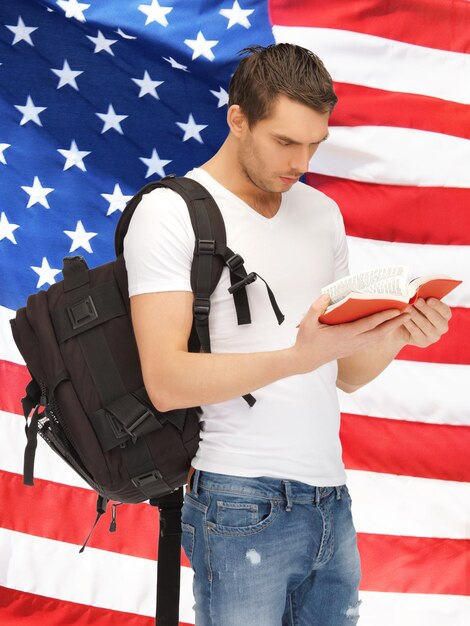 Immagine luminosa di uno studente in viaggio con zaino e libro sopra la bandiera americana