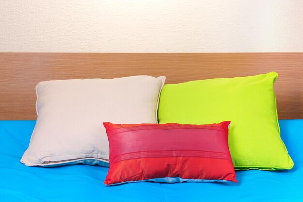 Bright pillows on bed on beige background