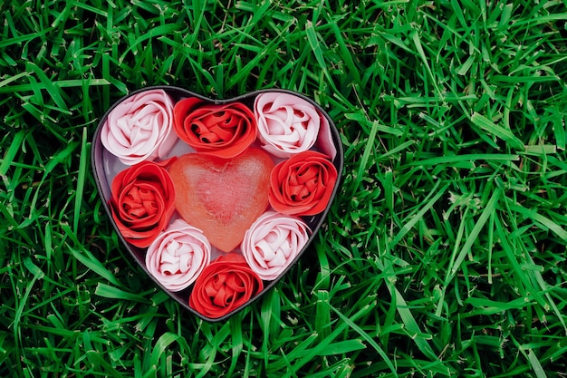 Bright pink and red roses made of soap shavings with hearts on green grass in a heartshaped box valentines romantic copy space mather day