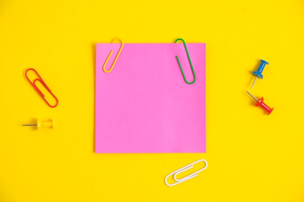 Bright pink sticker for notes and stationery buttons with paper clips yellow background