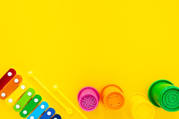 Bright rainbow children's xylophone and pyramid on a yellow background. Composition with children's toys, top view, flat lay, copy space.