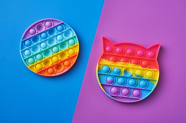 Bright rainbow toy antistress for children and adults on a colorful background. New popular silicone popit toy.