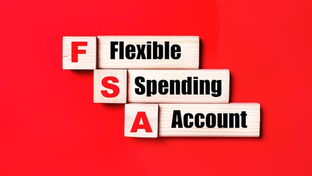 On a bright red background wooden cubes and blocks with the text FSA Flexible Spending Account Manufacturing of wooden toys