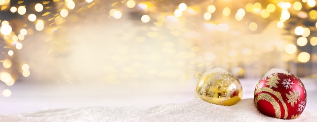 ボケ味のメリークリスマスとゴールドの背景に雪の上の真っ赤なクリスマスボール