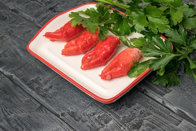 Bright red crab claws with lots of parsley in a plate on a wooden table