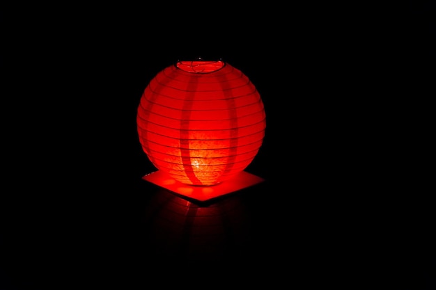 Una lanterna galleggiante rossa brillante nell'acqua nera