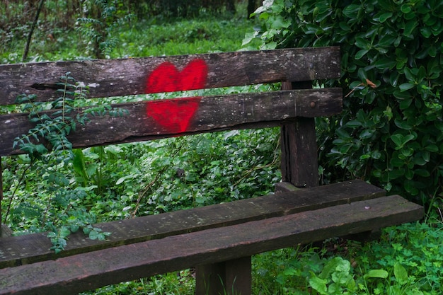 Photo bright red heart painted on the back of a wooden bench in the park