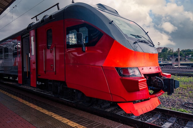 A bright red train stands on the platform of the railway station in the city Passenger Transportation