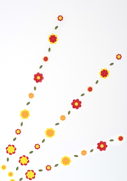 Bright red yellow orange paper flowers on white background spring summer concept flat lay style with