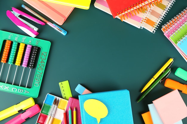 Bright school supplies on blackboard