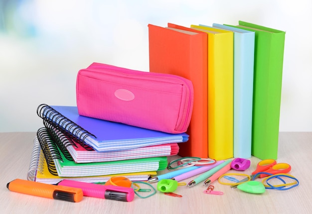 Bright school supplies on table on light background