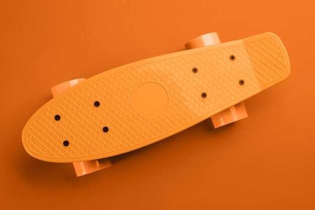 Photo bright skateboard on orange background top view