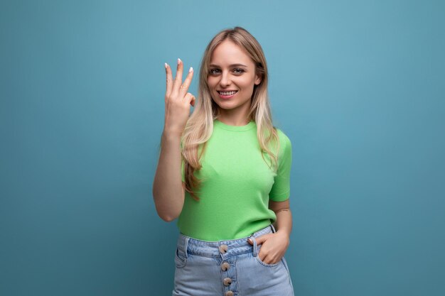 Bright smiling young woman in casual outfit showing three fingers on blue background