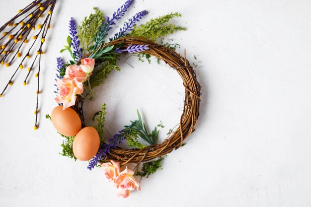 Bright spring flowers, wreath with easter eggs on grey