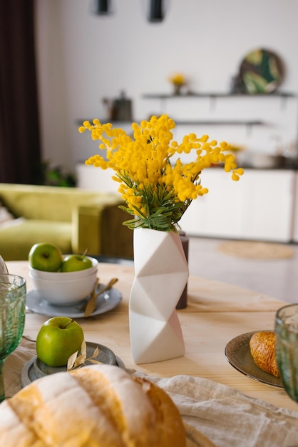 Bright spring mimosa in a ceramic geometric vase in the decor serving a festive or home table