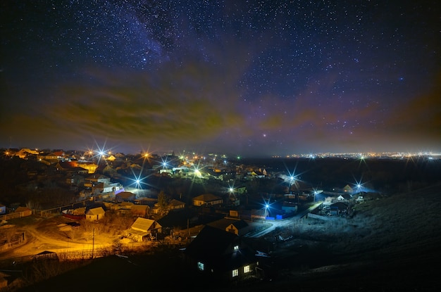 Photo the bright stars of the milky way with clouds in the night sky over the city