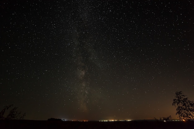 Bright stars in the night sky above the city with street lighting