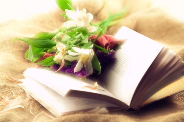 Bright still life with book and flowers. Soft focus.