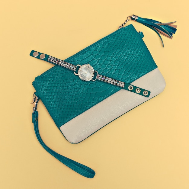 Bright stylish accessory Ladies. Green clutch and watch on a yellow background.