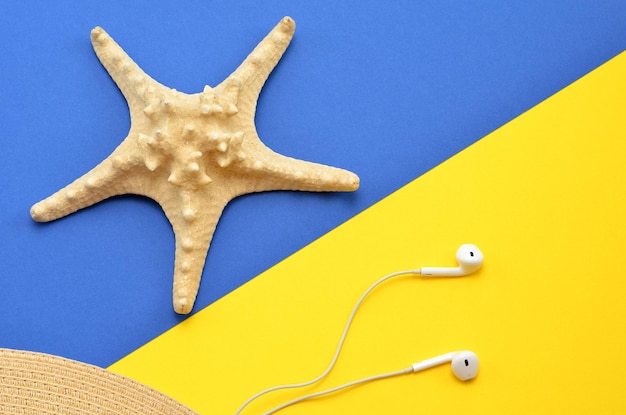 Bright summer background starfish headphones and a hat on a yellowblue background