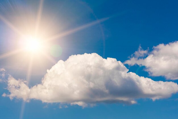 Bright sun on blue sky with white fluffy clouds background