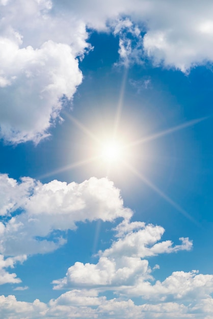 Bright sun on blue sky with white fluffy clouds background