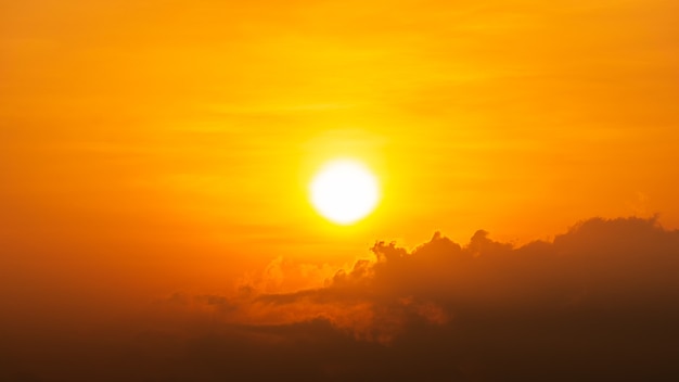 オレンジ色の空の自然な背景に明るい太陽と雲