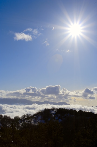 Bright sun above the cloudy mountains is lighting right to the camera