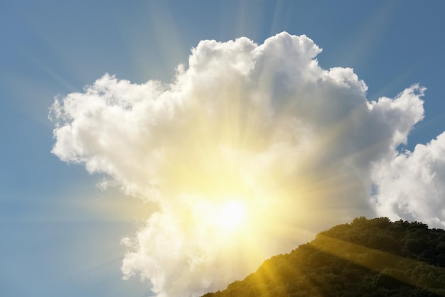 Bright sun rays in the blue sky over the green mountains