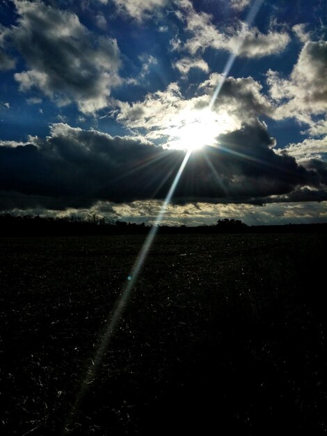 Foto il sole splendente splende sul campo contro un cielo nuvoloso