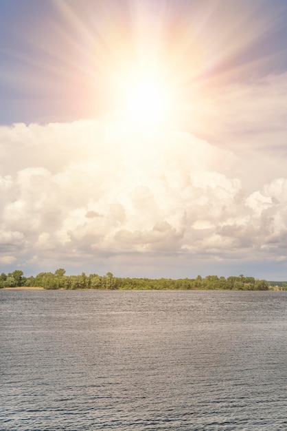 Bright sun in the sky over the water and the forest